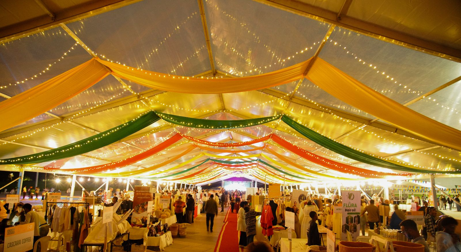 ENQU bazaar tent draped in colour and strung with twinkling lights above the vendor aisles